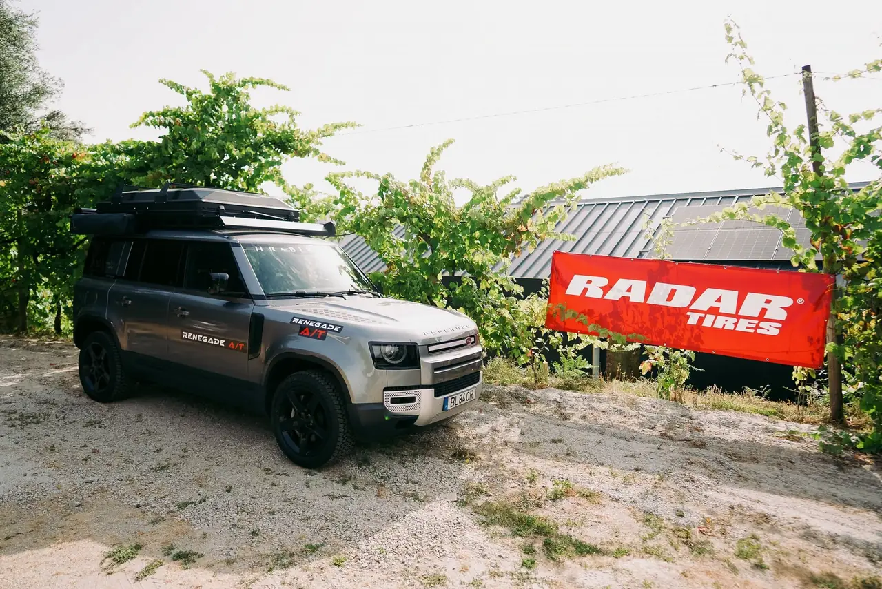 Land Rover Defender com pneus Radar Renegade A/T junto a um banner da Radar Tires numa vinha no Norte de Portugal